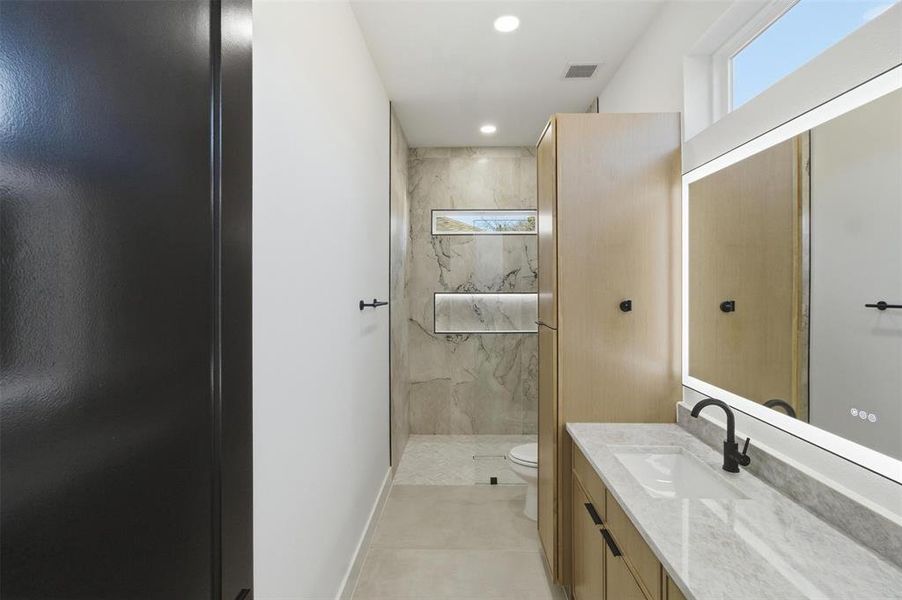 Bathroom with vanity, a marble finish shower, and recessed lighting