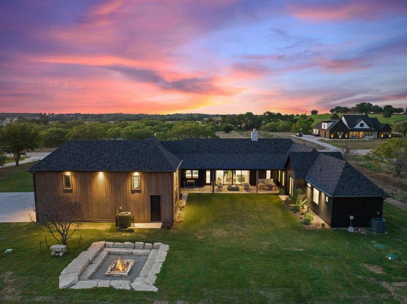 View of front facade with a yard, a fire pit, central AC unit, and a patio