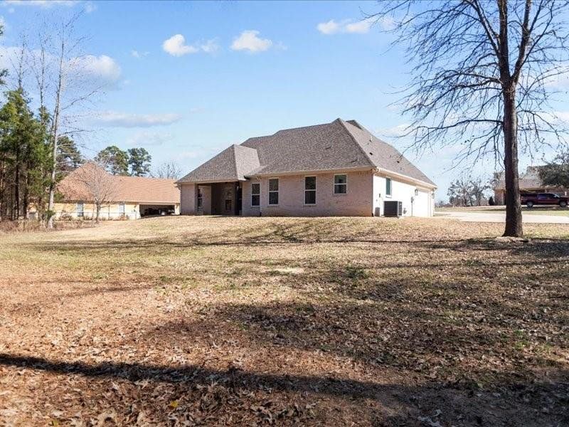 Back of property featuring a lawn, brick siding, and a shingled roof