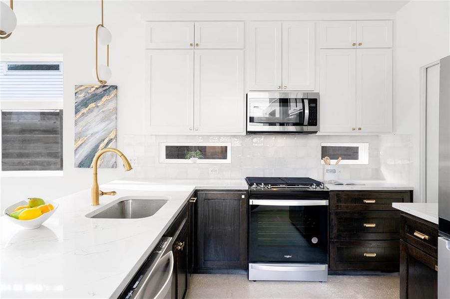 Beautiful lower cabinets complimented by clean white upper cabinetry with gold fixtures