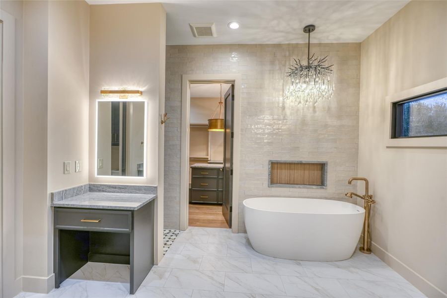Spa-inspired bath with dual vanities, soaking tub, large walk-in shower, makeup station & custom fixtures.