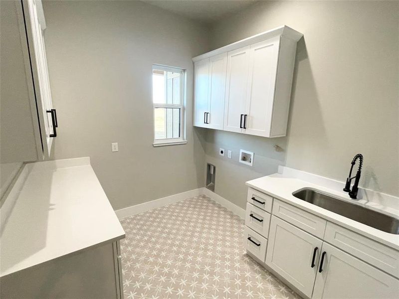 Spacious laundry room with plenty of storage space, oversized sink with sprayer and folding space.