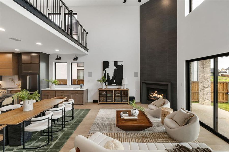 Living room with a towering ceiling, a fireplace, plenty of natural light, and light wood finished floors Living room with a towering ceiling, a fireplace, plenty of natural light, and light wood finished floors
