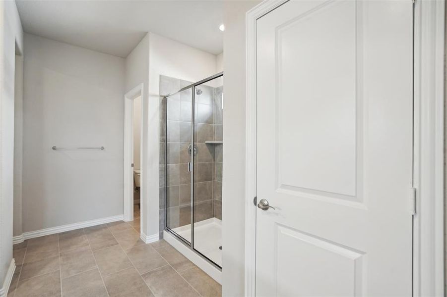 Bathroom featuring walk in shower, tile patterned flooring, and toilet