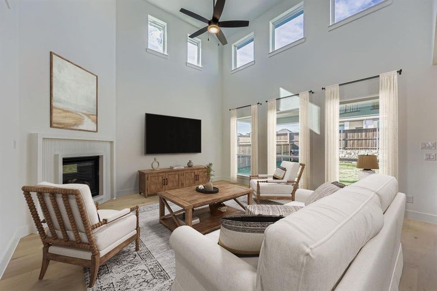 Virtually staged photo - Living area featuring light wood finished floors, a glass covered fireplace, and ceiling fan