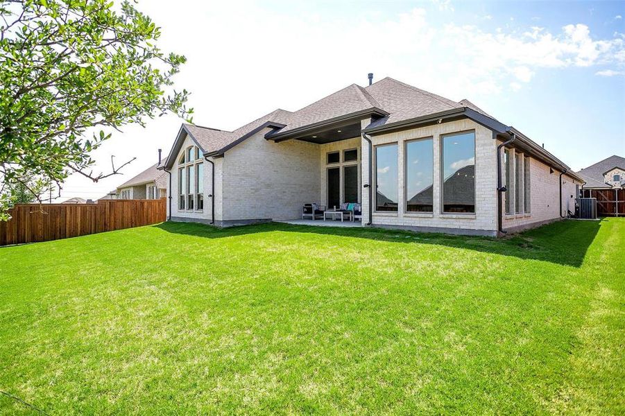 Rear view of property with brick siding, a fenced backyard, a patio, and a shingled roof Rear view of property with brick siding, a fenced backyard, a patio, and a shingled roof