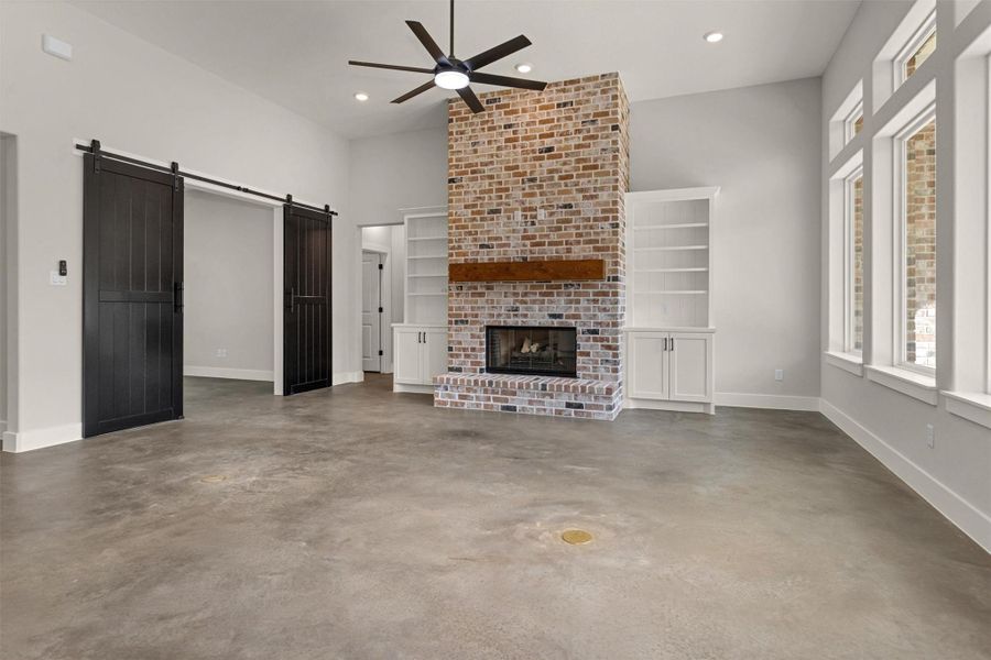 The living area is a warm and inviting space designed for both comfort and connection. A stunning gas log fireplace, bricked from floor to ceiling, serves as a dramatic focal point — adding texture, height, and timeless character to the room.