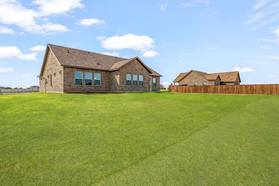 Rear view of house featuring brick siding and roof with shingles