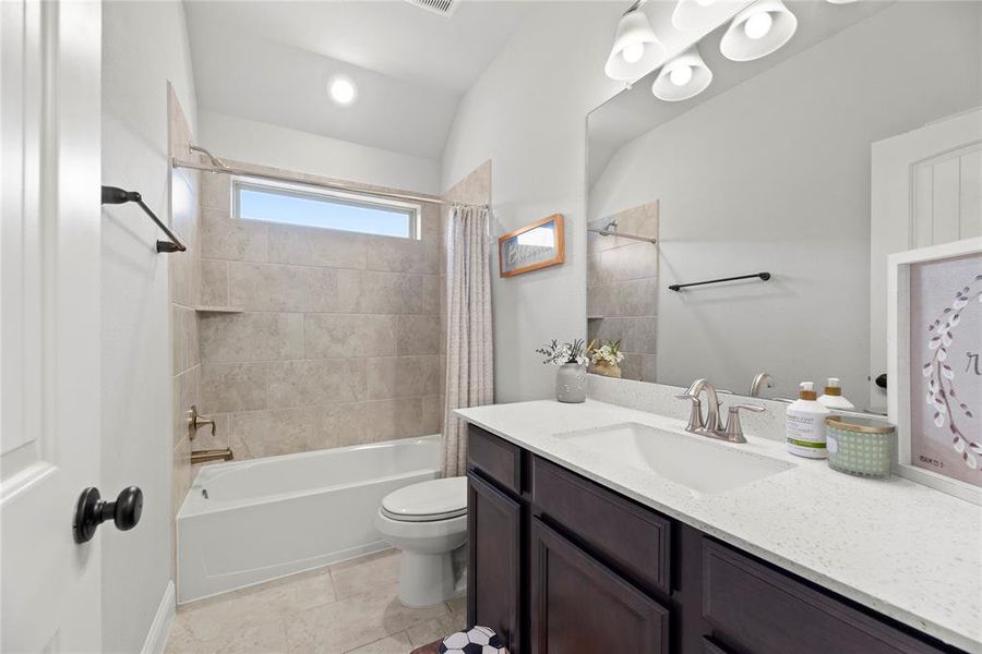 This restroom features a bathtub with shower, a large mirror over a vanity with ample counter space, and a frosted glass window providing natural light.