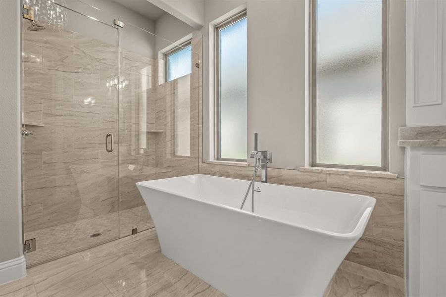 Full bath featuring a soaking tub, a shower stall, tile walls, and light marble finish flooring