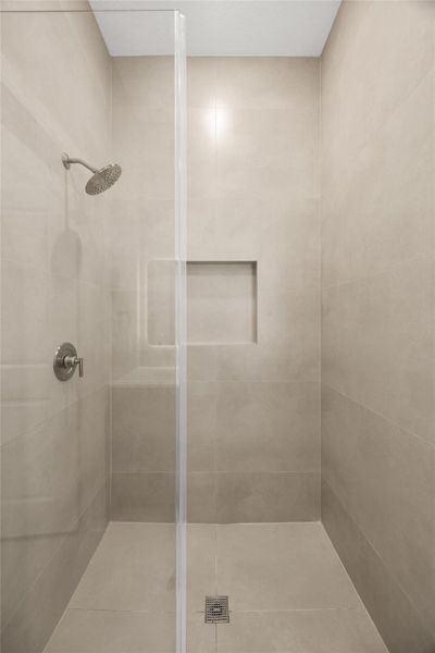 Oversized walk-in shower with frameless glass enclosure and built-in niche.