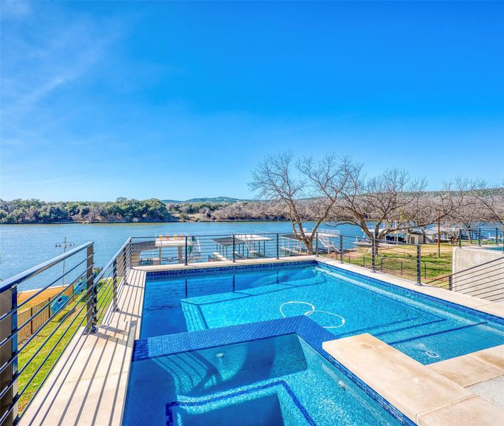 View of pool with a water view, a hot tub, and patio surround.