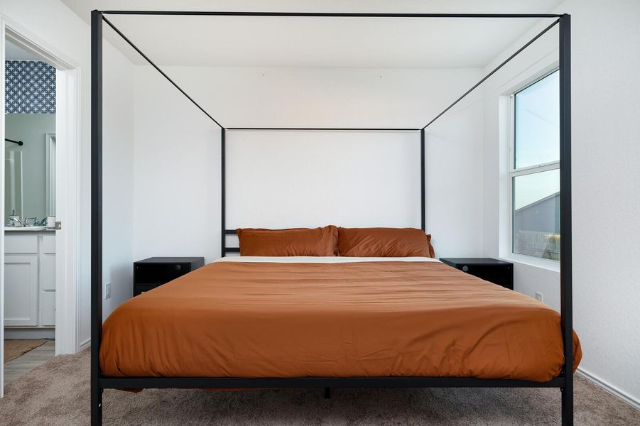 Carpeted bedroom featuring ensuite bath and baseboards Carpeted bedroom featuring ensuite bath and baseboards