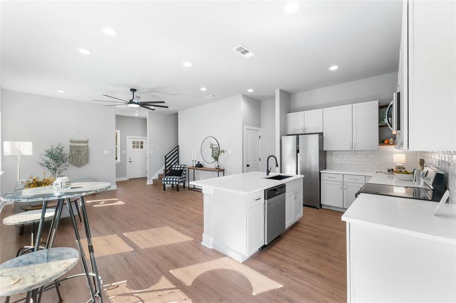 Kitchen featuring tasteful backsplash, an island with sink, a ceiling fan, appliances with stainless steel finishes, and recessed lighting