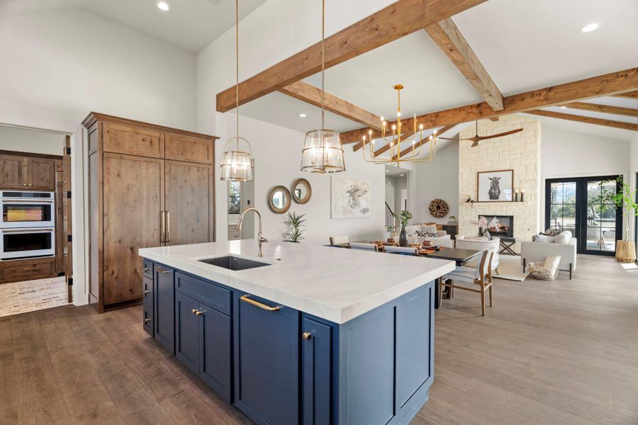 Kitchen with lapis blue cabinetry, open floor plan, vaulted ceiling, and massive sized refrigerator/freezer.