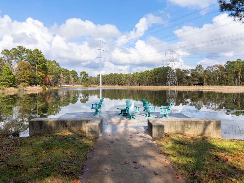 Peaceful neighborhood waterfront scene with a wooden deck and turquoise chairs overlooking a serene lake. It's a perfect spot for relaxation and enjoying nature.