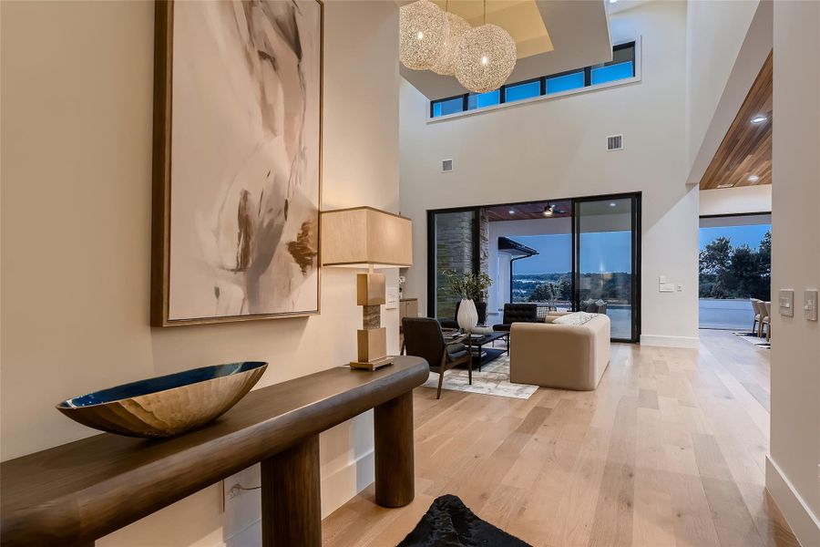 This spacious living area features high ceilings, light wood flooring, and large sliding glass doors