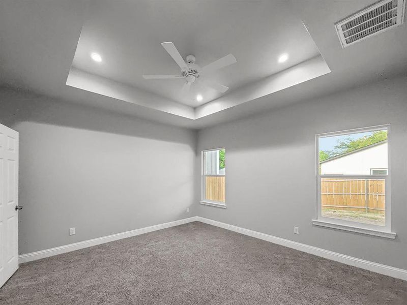 Primary bedroom featuring a tray ceiling, recessed lighting, a ceiling fan, and baseboards Primary bedroom featuring a tray ceiling, recessed lighting, a ceiling fan, and baseboards