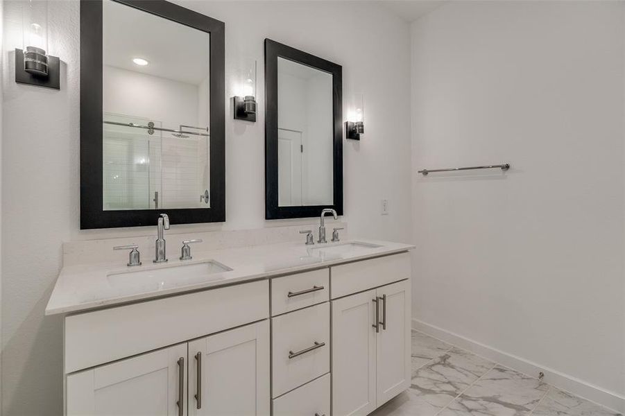 Full bathroom featuring double vanity, a stall shower, and light marble finish flooring Full bathroom featuring double vanity, a stall shower, and light marble finish flooring