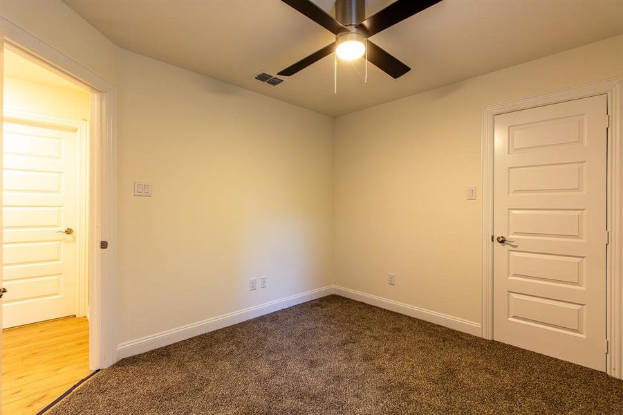 Empty room featuring dark carpet and a ceiling fan Empty room featuring dark carpet and a ceiling fan