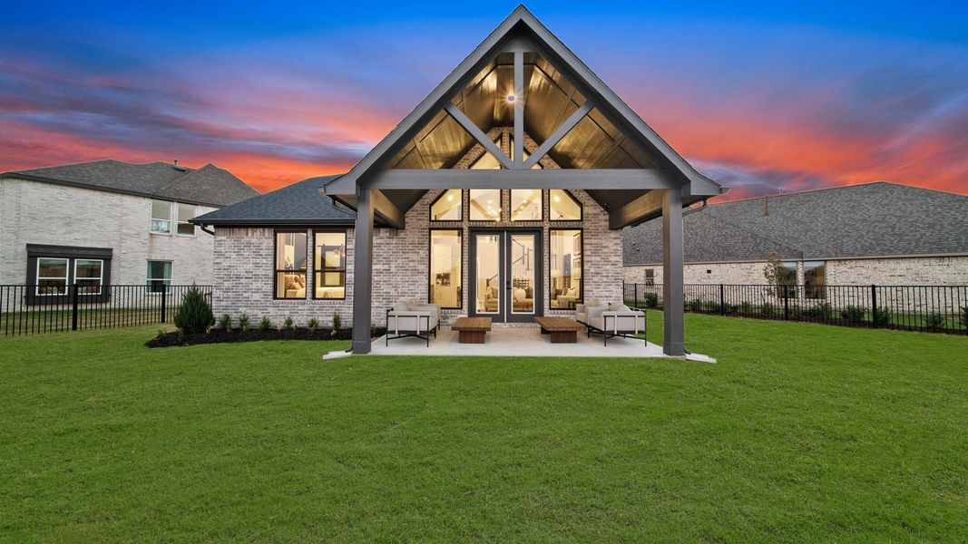 At dusk, the back of this home glows with warm lighting casting a wash over the seating area while the fading sky adds a calm, evening backdrop. At dusk, the back of this home glows with warm lighting casting a wash over the seating area while the fading sky adds a calm, evening backdrop.