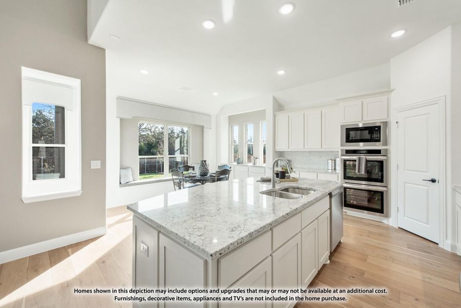 Kitchen with granite island, white cabinets, stainless steel appliances, and hardwood floors open to living area