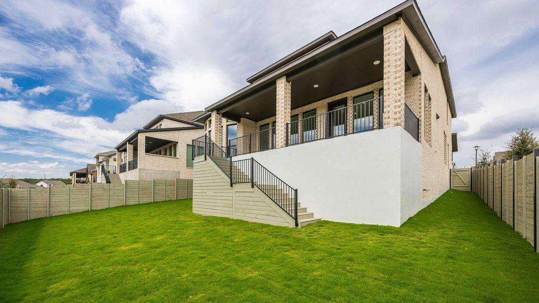 Rear view of house with stairway, a fenced backyard, a balcony, and a patio area