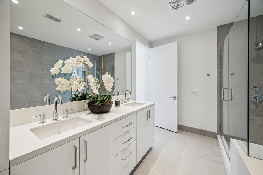 Serene primary bathroom with neutral color scheme, plentiful storage.