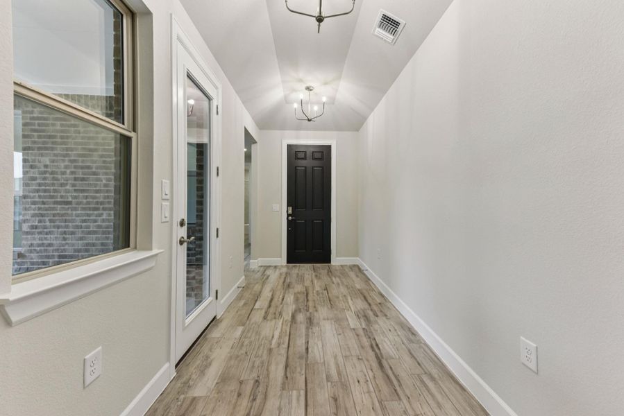 Entryway with wood finished floors and a chandelier