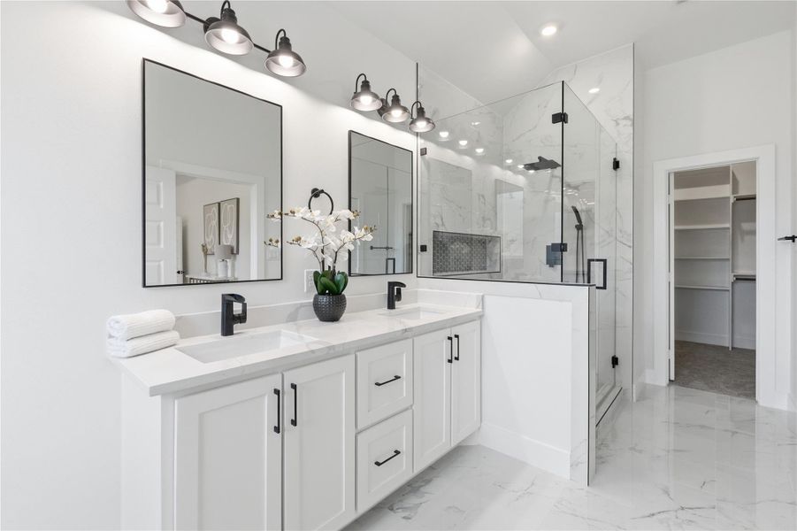 Full bath featuring double vanity, a spacious closet, a marble finish shower, and light marble finish flooring