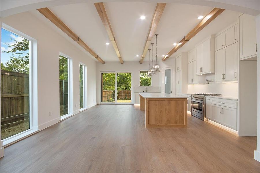 Kitchen featuring white cabinetry, a chandelier, beamed ceiling, gas range, and open floor plan