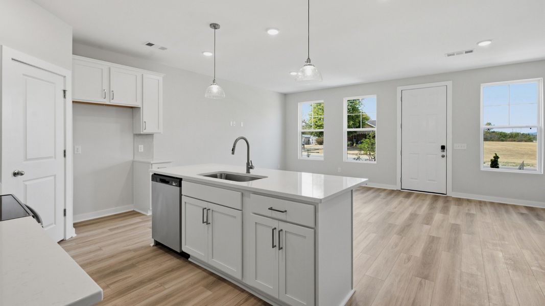 White island under hanging lights paired with sink and dishwasher