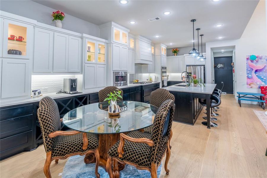 Dining room with light wood finished floors and recessed lighting