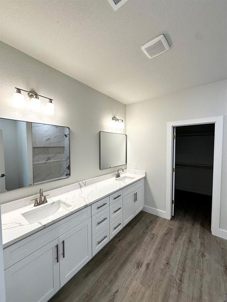 Picture of ensuite bath with white shaker cabinets with soft closing, white quartz countertops, designer lightning, and luxury vinyl flooring