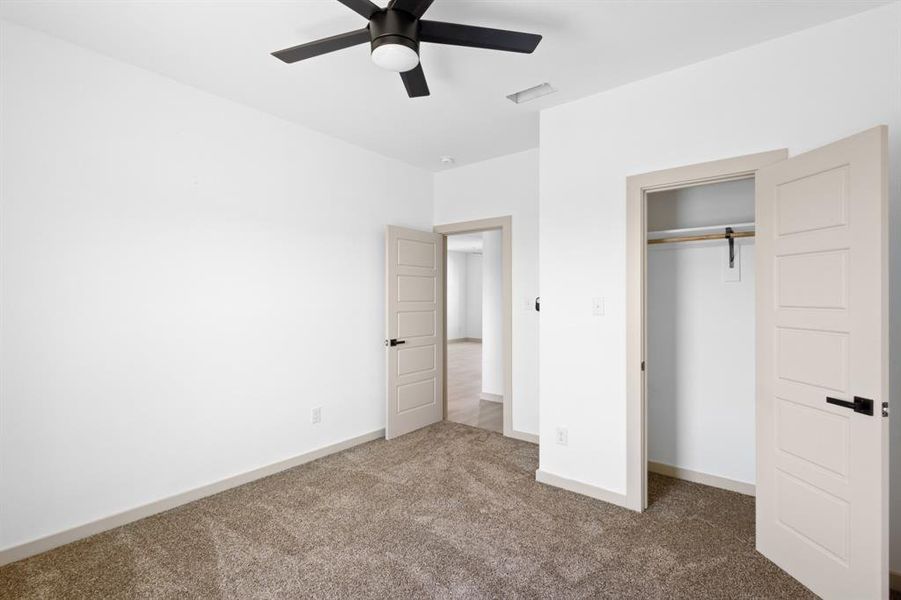 Unfurnished bedroom featuring carpet flooring, visible vents, baseboards, a closet, and ceiling fan Unfurnished bedroom featuring carpet flooring, visible vents, baseboards, a closet, and ceiling fan