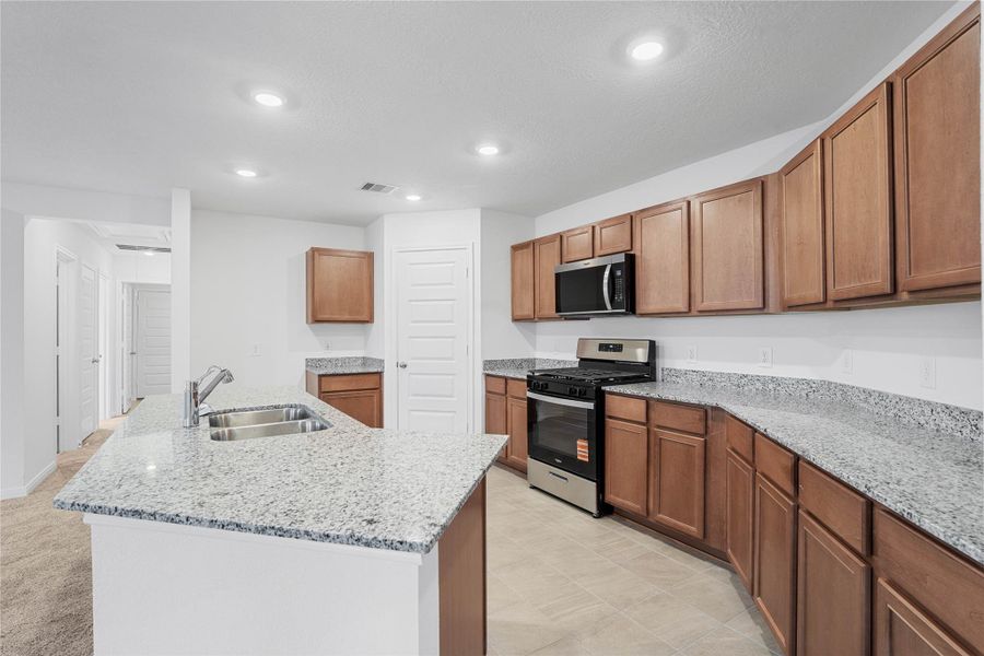 A true chef’s dream, this expansive kitchen boasts high ceilings, rich stained Woodmont Cody cabinets in Toffee stain, granite countertops in Luna Pearl, stainless steel appliances, a modern tile backsplash, recessed lighting, an island with a double sink, and a walk-in pantry—all with a clear view of the spacious Great Room. A true chef’s dream, this expansive kitchen boasts high ceilings, rich stained Woodmont Cody cabinets in Toffee stain, granite countertops in Luna Pearl, stainless steel appliances, a modern tile backsplash, recessed lighting, an island with a double sink, and a walk-in pantry—all with a clear view of the spacious Great Room.