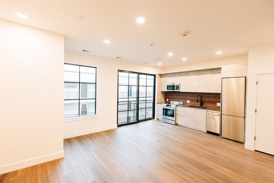 Kitchen with stainless steel appliances, recessed lighting, light wood finished floors, white cabinetry, and backsplash