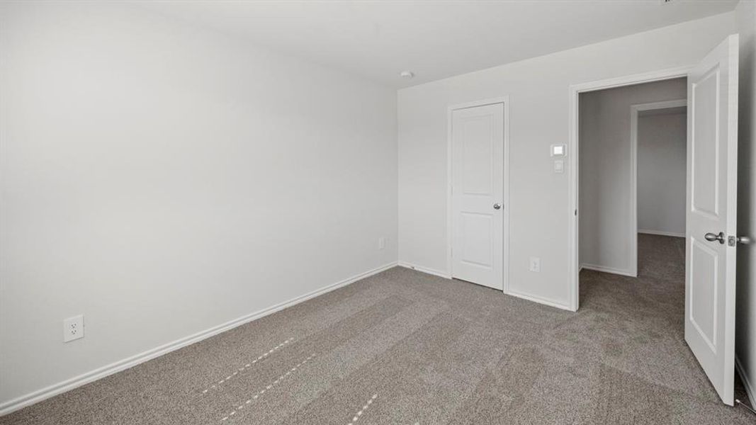 Unfurnished bedroom featuring light carpet and baseboards