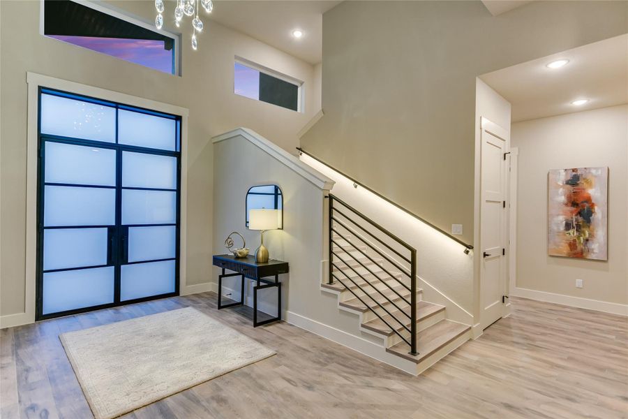 Entryway with a high ceiling, light tile wood-style floors, stairway, and recessed lighting Entryway with a high ceiling, light tile wood-style floors, stairway, and recessed lighting