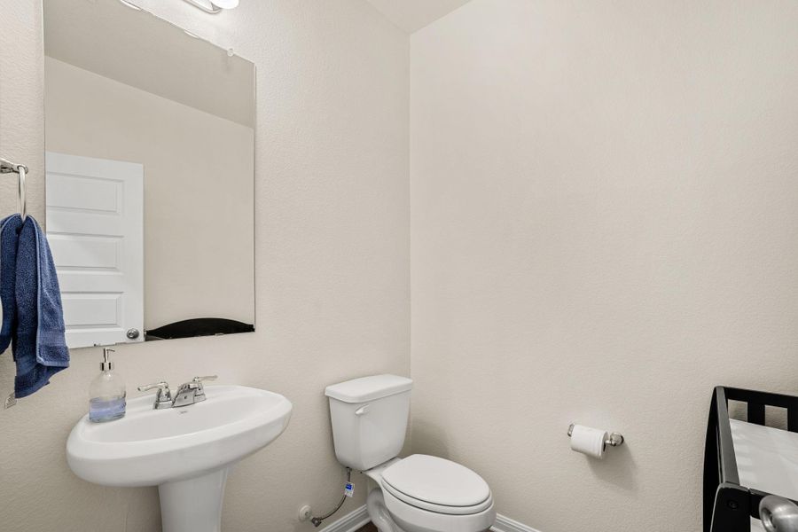 A well-appointed half-bath with a pedestal sink provides essential convenience.