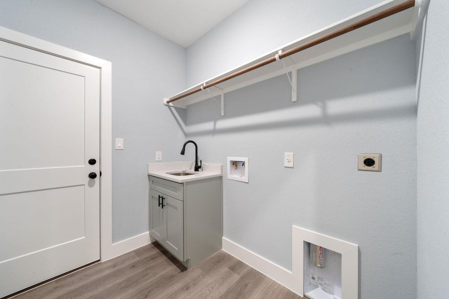 Utility room featuring wood-finish flooring, a white flat-panel door, and light blue walls