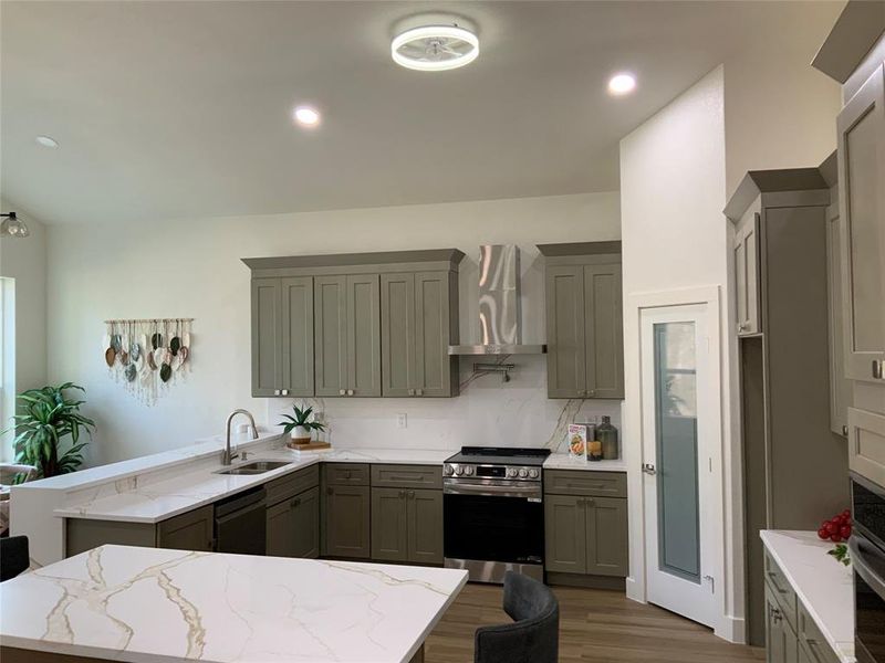 Kitchen featuring stainless steel appliances, light stone counters, dark wood-style floors, a peninsula, and backsplash Kitchen featuring stainless steel appliances, light stone counters, dark wood-style floors, a peninsula, and backsplash