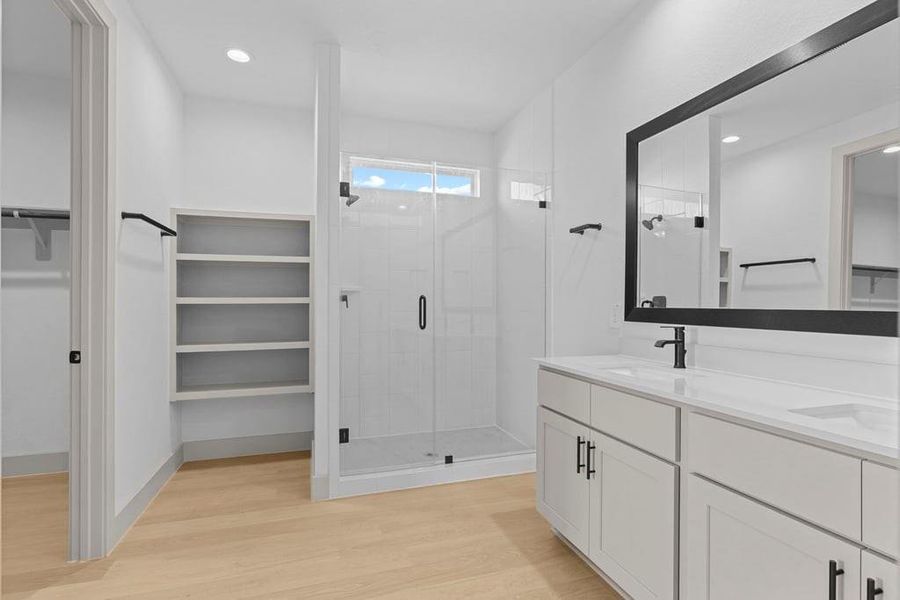 Modern primary bathroom with double vanities, quartz countertops, and a glass-enclosed shower with a walk-in closet. Modern primary bathroom with double vanities, quartz countertops, and a glass-enclosed shower with a walk-in closet.