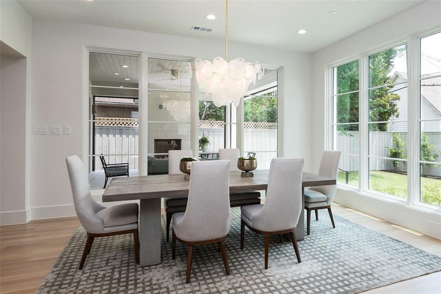 Dining room featuring a healthy amount of sunlight, light wood-type flooring, and a chandelier