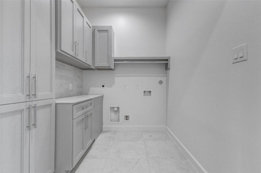 Dedicated upper-level utility room with upper and lower cabinetry, countertop workspace, and built-in shelving for organization. Durable tile flooring and neutral finishes ensure practicality while maintaining the home’s refined aesthetic. Conveniently located near the bedrooms for everyday ease.