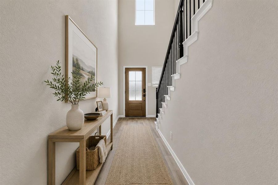 *Virtually Staged* Foyer featuring wood-finish flooring, a wood entry door with frosted glass, and a two-story ceiling with a high window