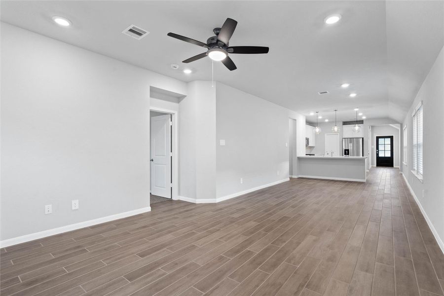 This expansive view from the back of the house showcases a seamless, open-concept layout that creates a warm and inviting path for guests, drawing the eye past the heart of the home toward the welcoming front entryway