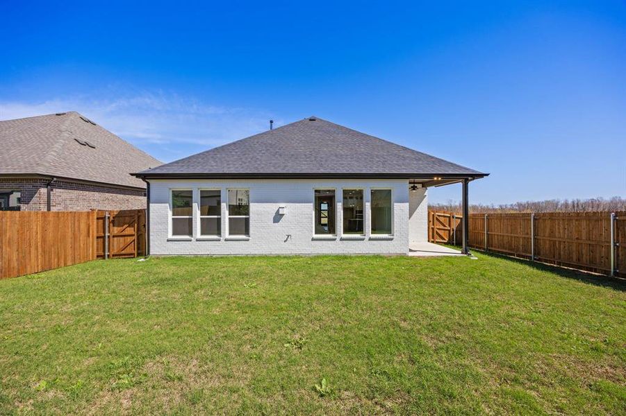 Back of property featuring a gate, a fenced backyard, a patio, brick siding, and a shingled roof