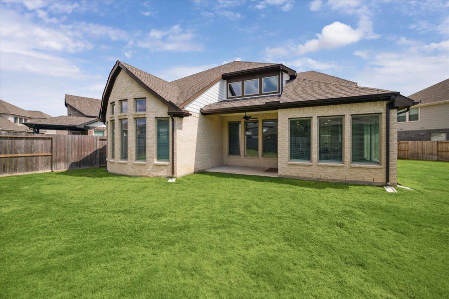 The spacious backyard is a true highlight, featuring lush green grass, a generous side yard, and a fully fenced design for privacy. A covered patio extends the living space outdoors—perfect for entertaining or simply relaxing in this exquisite setting.