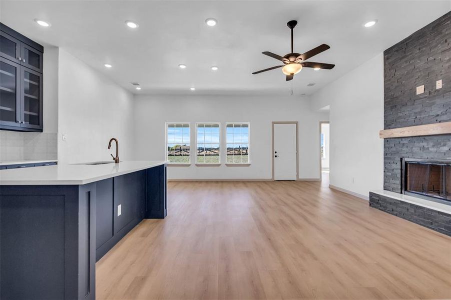 Kitchen with ceiling fan, sink, a fireplace, and light hardwood / wood-style flooring